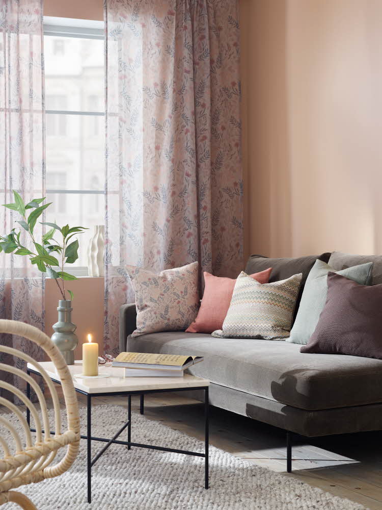 stue med grå sofa og lyse, blomstrende gardiner
