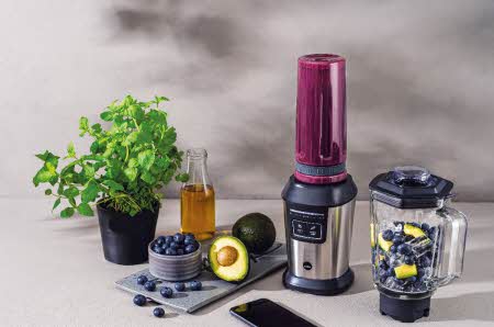 En blender i stål med tilbehør og urter, avocado og bær