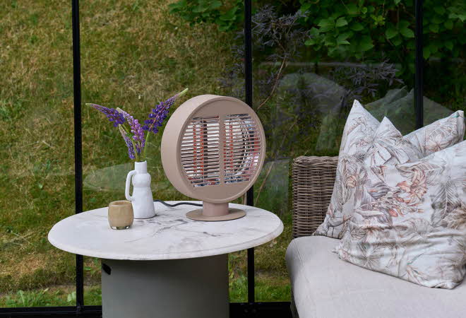 Et uteområde med en sofa og et bord med en varmelampe på.