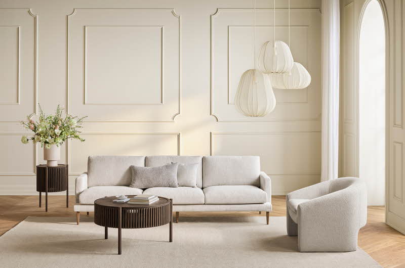 En stue med en hvit sofa, et stuebord, en lenestol og en sidebord med en plante på