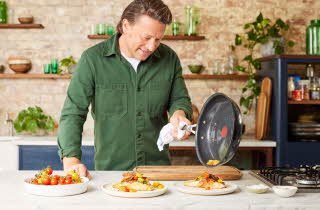 Jamie Oliver som heller mat han har laget fra stekepannen på en tallerken