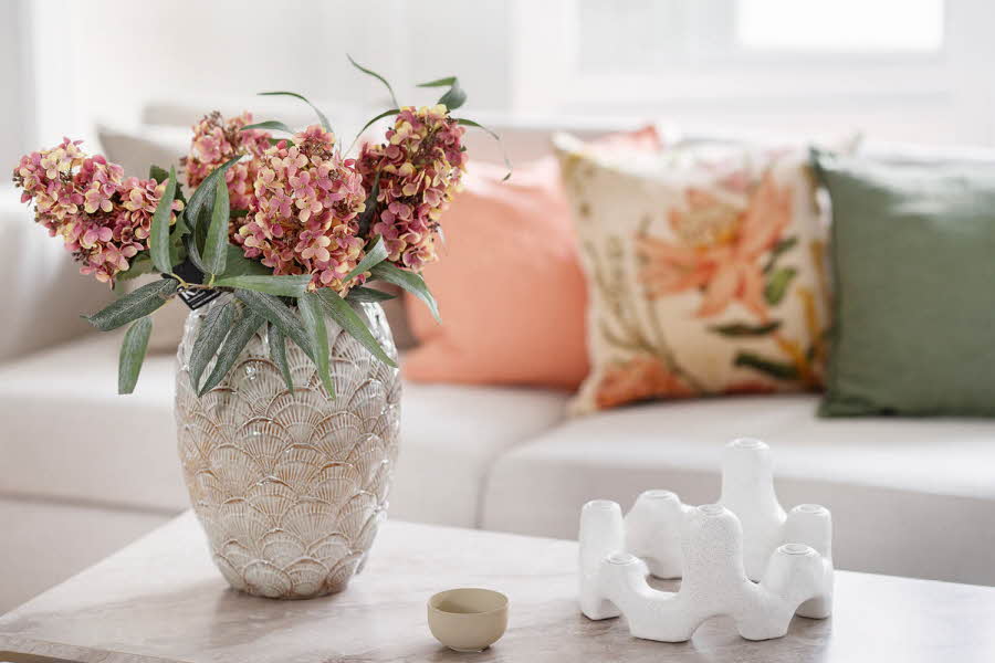 Et bord med en vase med blomster, og en hvit lysestake