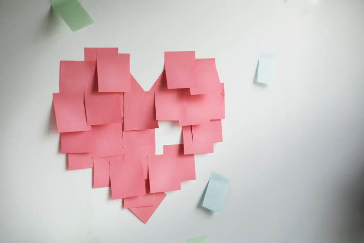 Hvit vegg med rosa post-it-lapper som utgjør en hjerteform