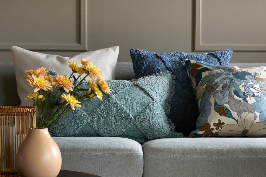Fargerike puter i sofa, gule blomster i vase