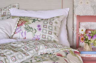 En seng trukket med et blomstrete sengesett