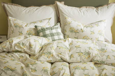 En seng med et sengesett med grønne og gule blomster