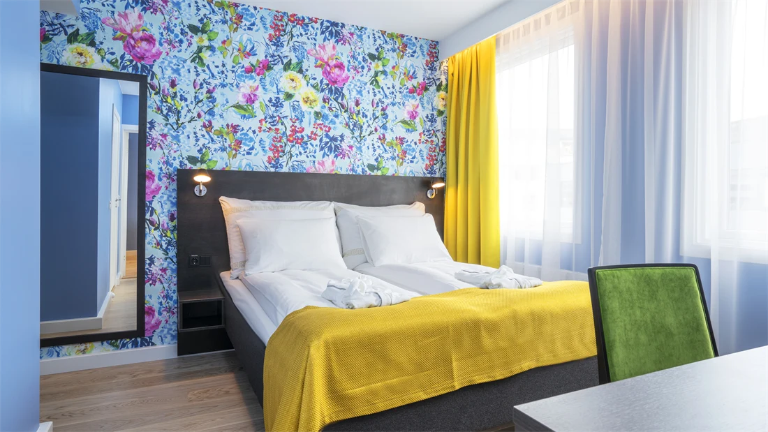 Dobbeltseng, blomstrete tapet, speil og skrivebord i suite på Thon Hotel Moldefjord