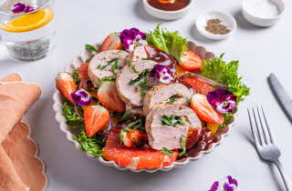 Tallerken med salat, inkludert kjøtt, jordbær, grapefrukt, salatblader og spiselige blomster.