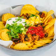 en bolle med nachos, løk, kjøtt, ost, tacosaus og mais