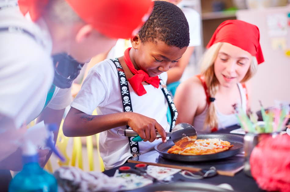 En gutt skjærer minipizza med pizzahjul