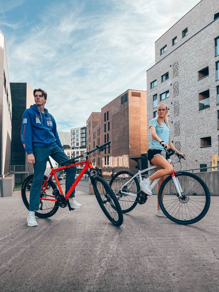 Mann og dame på sykkel med by i bakgrunn
