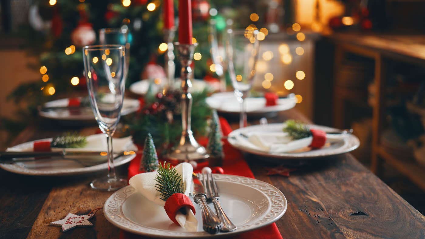 Juledekket bord med hvite asjetter, granbar og røde detaljer