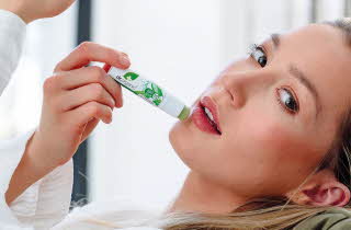 En kvinne som tar på seg Dr. Organic lip balm mens hun ser mot kameraet
