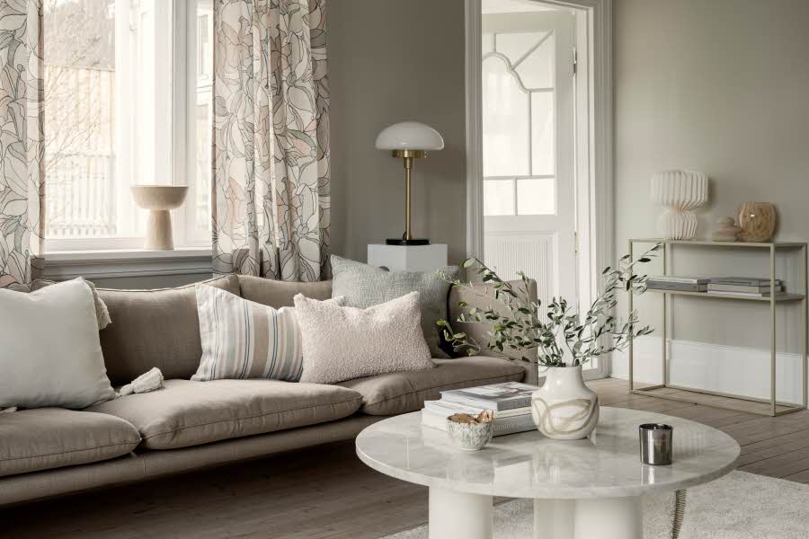 En innredet lys stue med sofa, bord og konsollbord