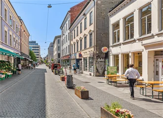 Handlegaten Torggata, sett fra øst til vest. Gågaten er pyntet med blomsterkasser og brostein. En grønnsakshandel på venstre side og restauranter med uteservering på høyre side.
