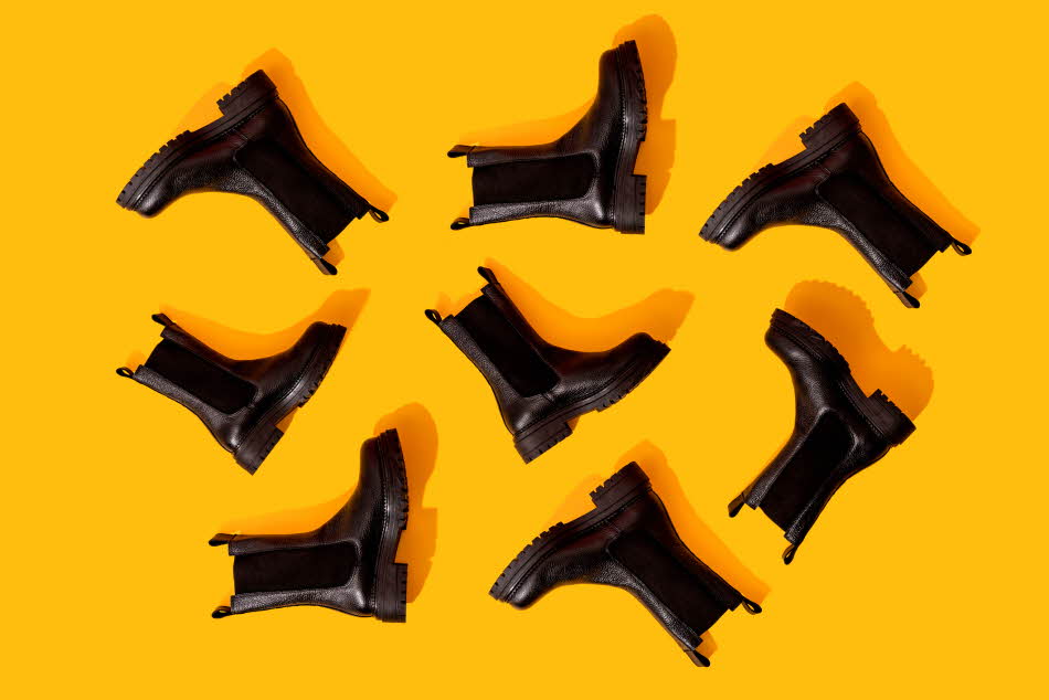 Svarte Chelsea-boots på oransje underlag i studio.