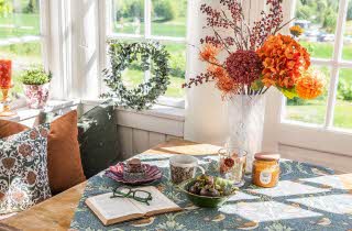 Et bord med en bok og en kaffekopp, med en vase med blomster