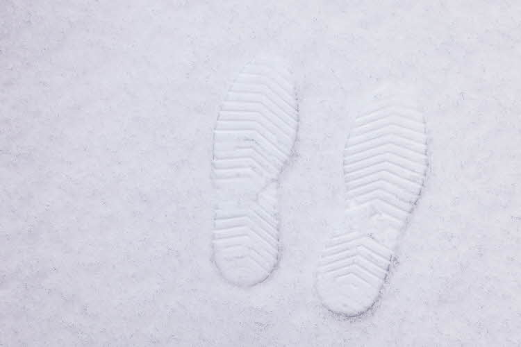Et par svarte, fôrede vinterstøvler som står plassert i snøen.