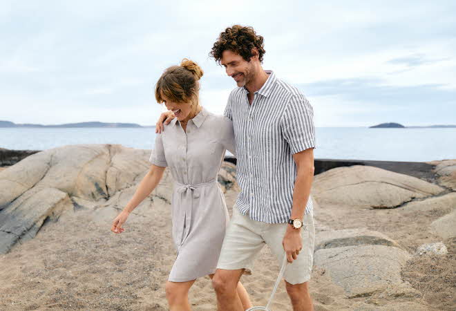 bilde av ett par som går på en stein strand i match klær