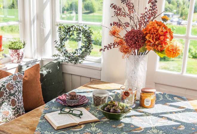 Et bord med en bok og en kaffekopp, med en vase med blomster