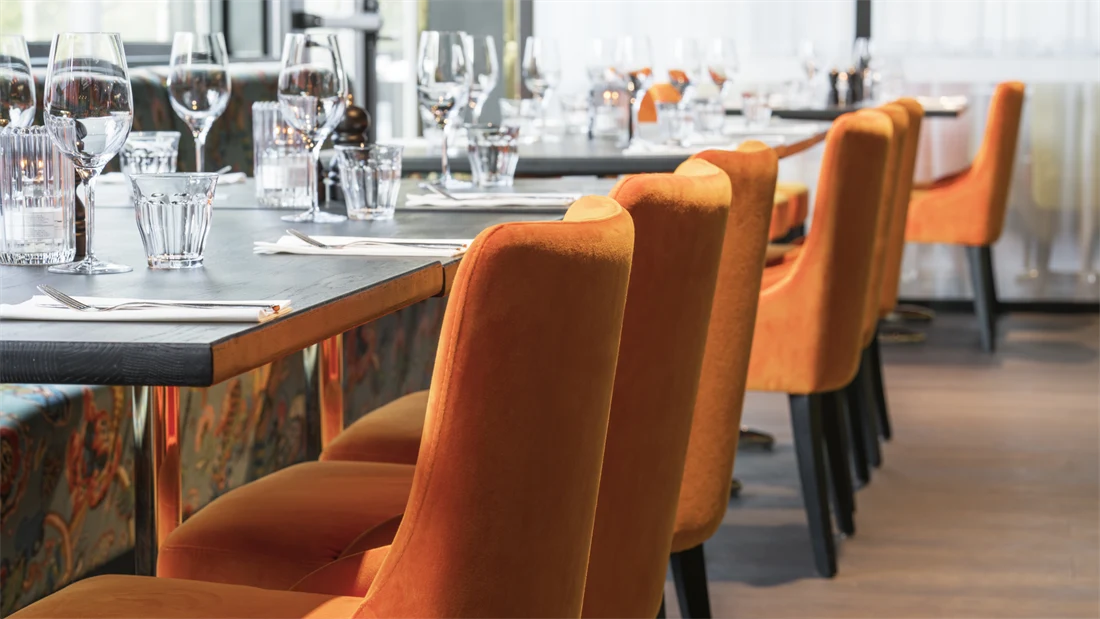 Frokostsal med orange stoler ved dekket bord på Thon Hotel Oslo Airport ved Gardermoen