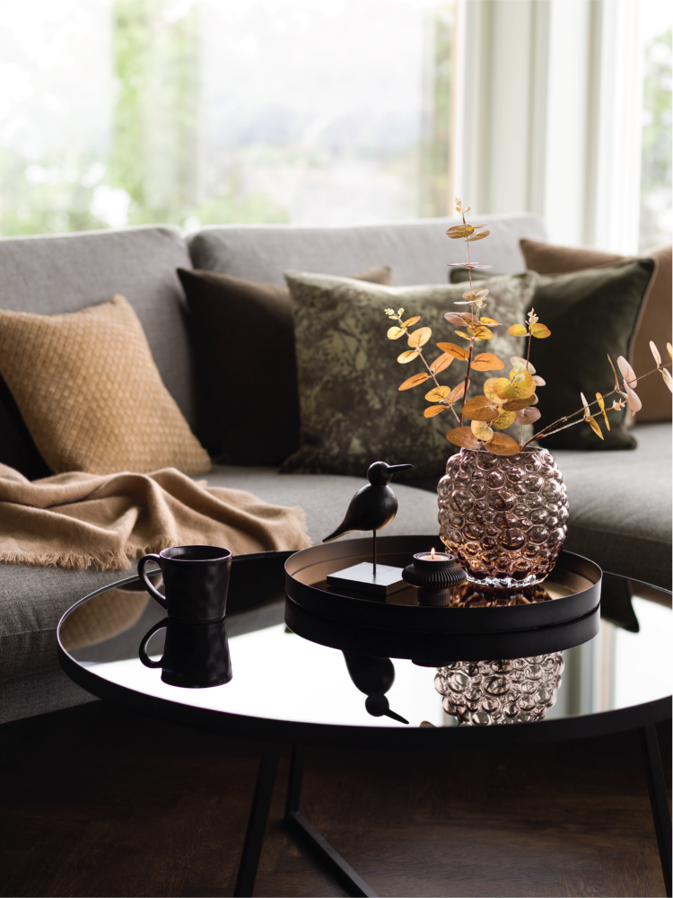 Sofa med bord dekket med vase med en kvist