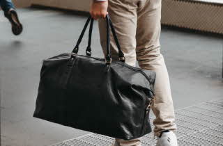 Person med stor svart skinnbag i et innendørs miljø.
