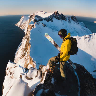 Mann i turklær står på toppen av et fjell 