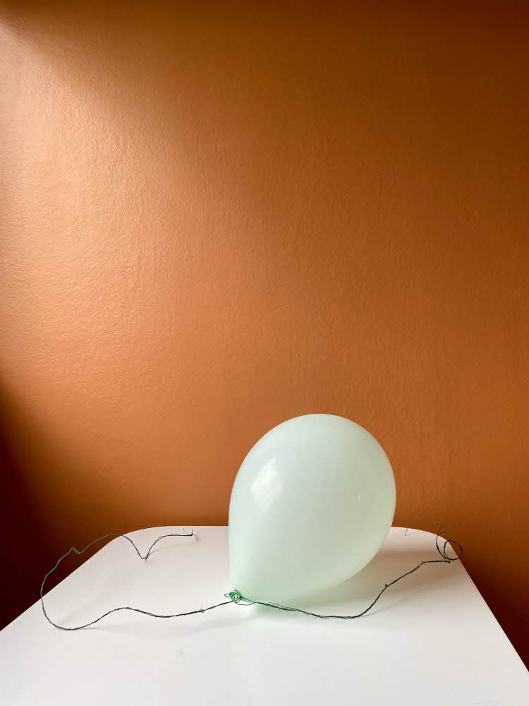 Oppblåst ballong med tråd som ligger på et bord med oransje bakgrunn