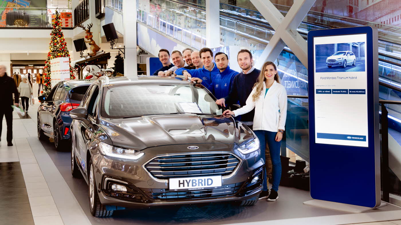 Utstillingsområde av Ford med mennesker bak en Ford Hybrid