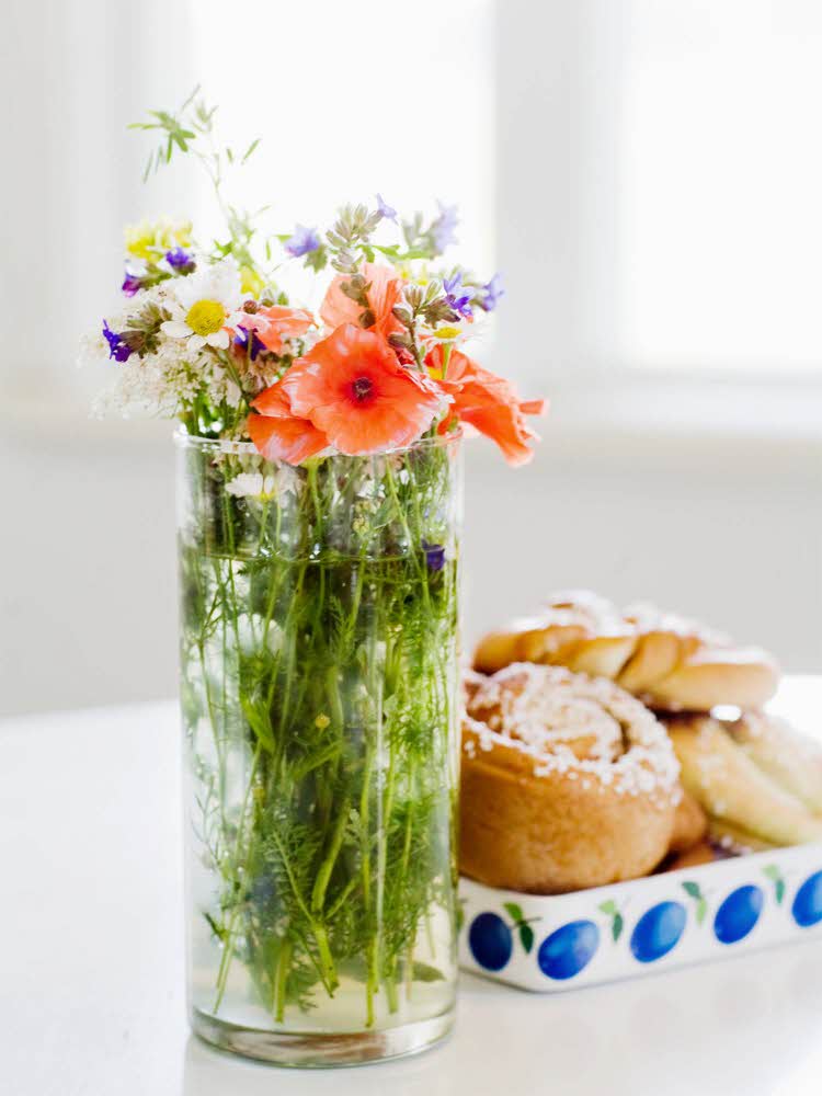 Markblomster i vase og fat med kanelboller på bord