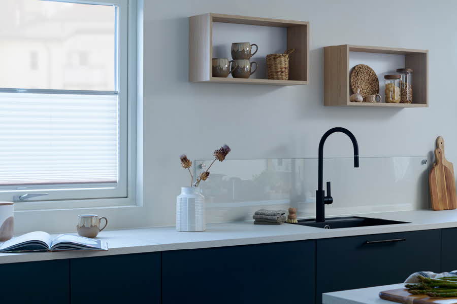 Moderne kjøkken med hvit kjøkkenbenk, svart kran og svarte skuffer.