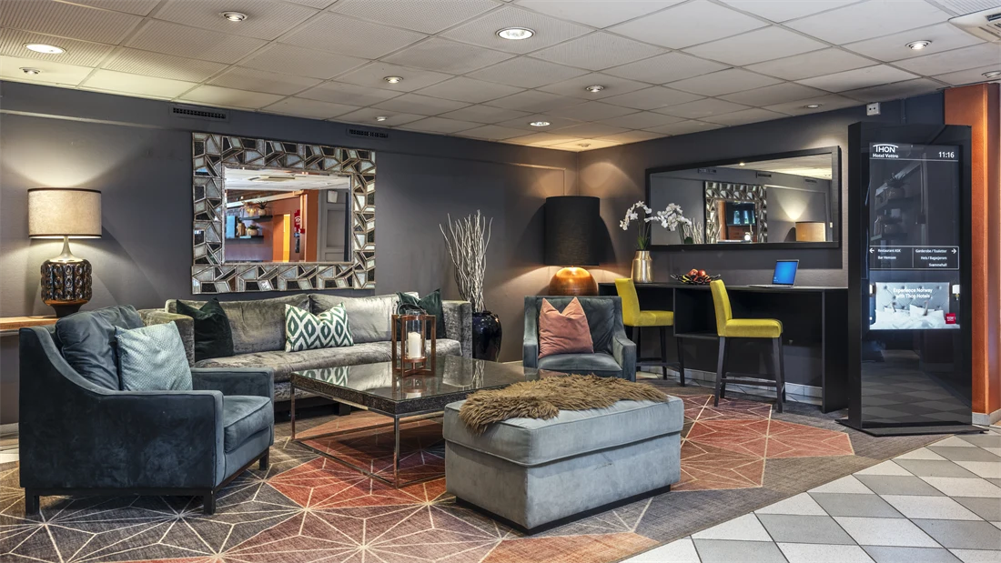 Sofa, lenestoler og puff i lobby med store speil på veggen.