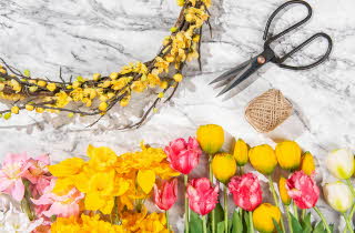 Diverse stilkblomster liggende ved siden av en saks og tråd