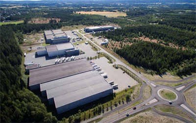 Dronebilde av stort lager- og logistikklokale, med rundkjøring og frodige omgivelser.