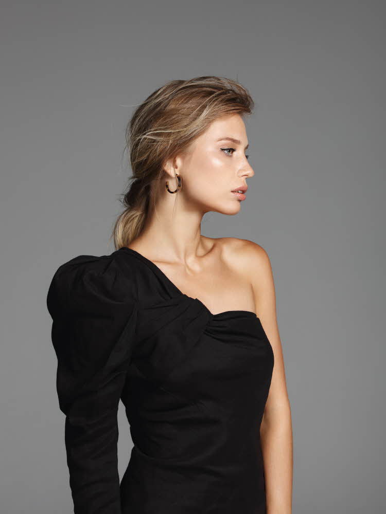 Modell med svart, enermet kjole Dame med glitterkjole med spaghettistropper og voluminøs chiffonbluse under. Rosa.