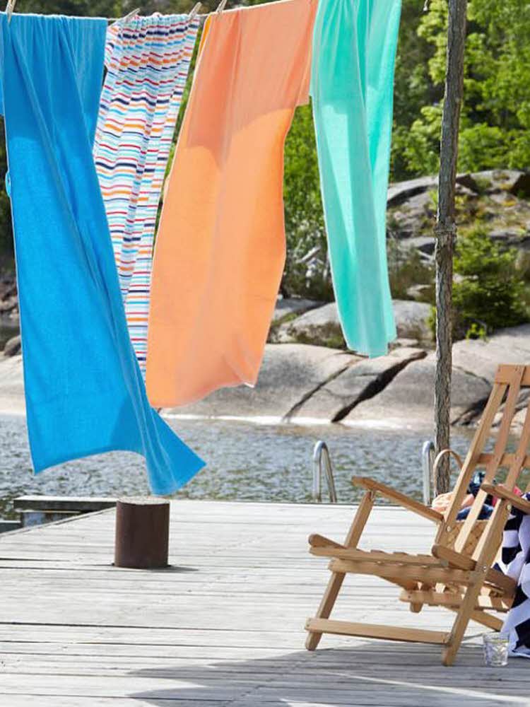 solseng i bambus på brygga med puter, pledd og lykter fargerike badehåndklær som henger til tørk på en brygge