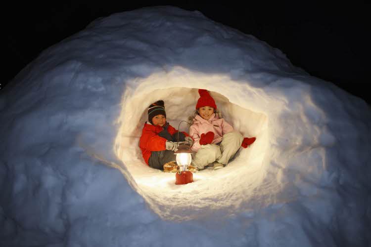 To barn med lykt inne i snøhule