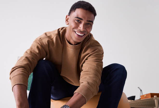 En mann som sitter på en gul treningsball i uformelt antrekk.