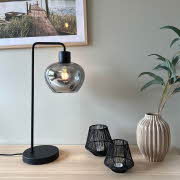 En Kelly bordlampe fra Lampehuset står på et konsollbord sammen med telysholdere og vaser