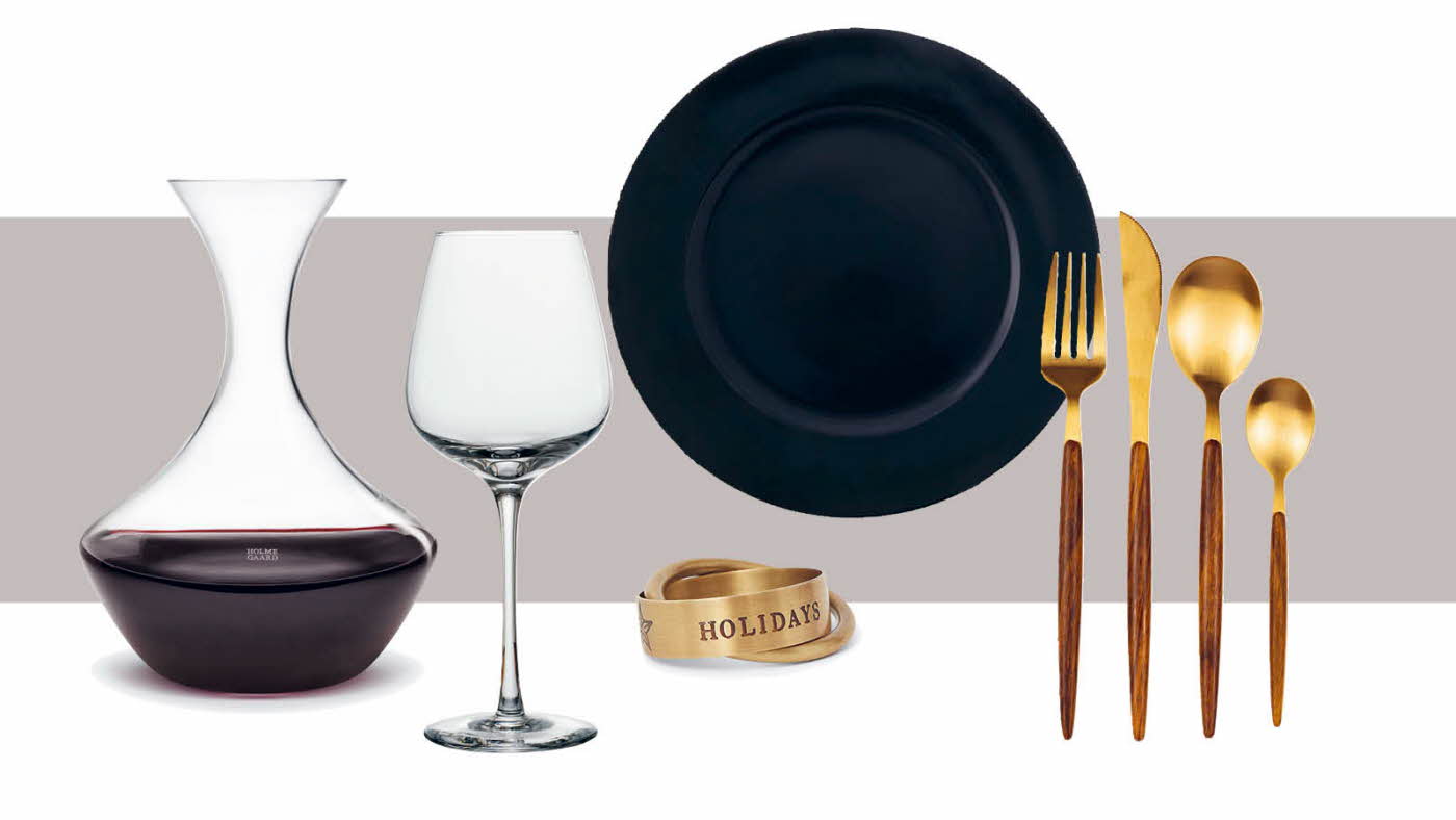 Vinkaraffel, vinglass, serviettringer, bestikk og sort tallerken