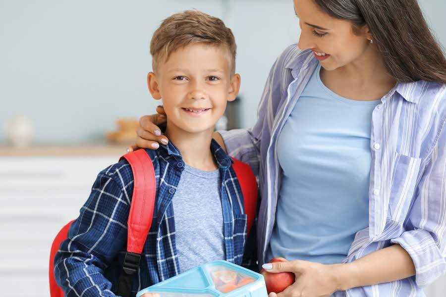 gutt med skolesekk og matboks sammen med mamman sin
