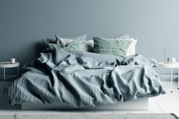 Lyseblått rom med en hvit seng med lyseblått sengetøy i lin