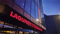 Nærbilde av fasaden til Lagunen Storsenter med skilt hvor senterets navn fremkommer med store, røde bokstaver.