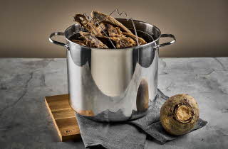 En pinnekjøttgryte med pinnekjøtt i står på en benk.