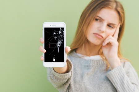 Dame som holder telefon med knust skjerm
