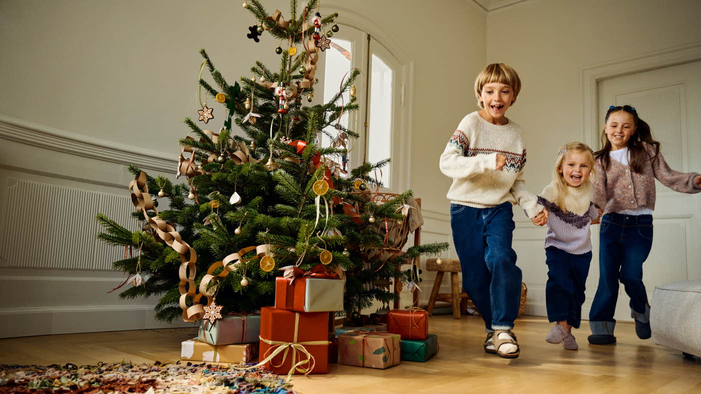Barn som løper i en julepyntet stue Barn som leker med musikkinstrument på en sofa Jente i kjole Barn som lener seg på en vegg