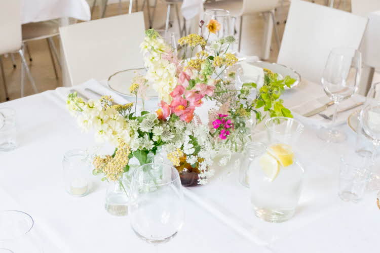 Hvitdekket bord dekorert med markblomster i små vaser