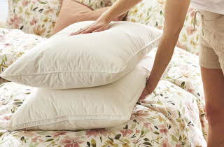 En kvinne som legger to dunputer på en seng