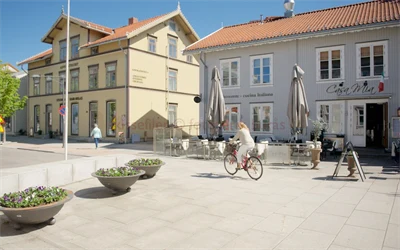 Bilde av en dame som sykler forbi inngangen til en restaurant